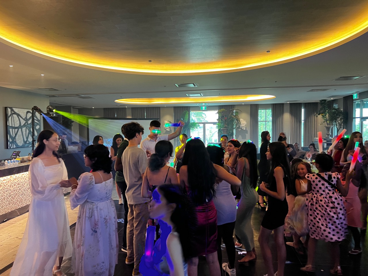 Invitados bailando con barras luminosas durante una Quinceañera