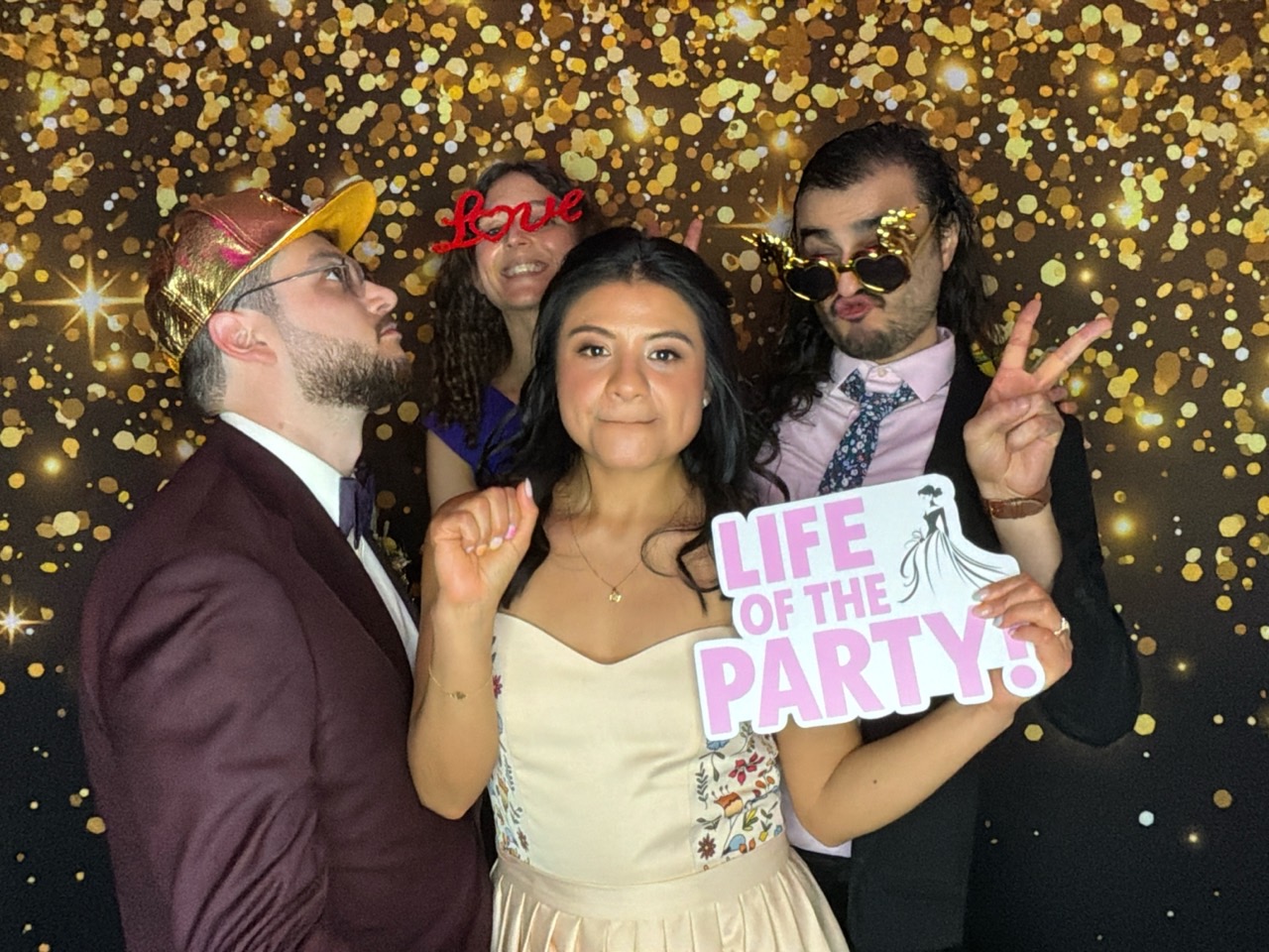 Newlyweds and friends in front of a gold digital photo booth backdrop